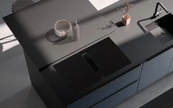 Edle schwarze Küche mit integrierter Spüle und Kochfeld. Design-Küchenarbeitsplatte mit klaren Linien, minimalistischer Gestaltung und stilvoller Dekoration in moderner Architekturbeleuchtung.